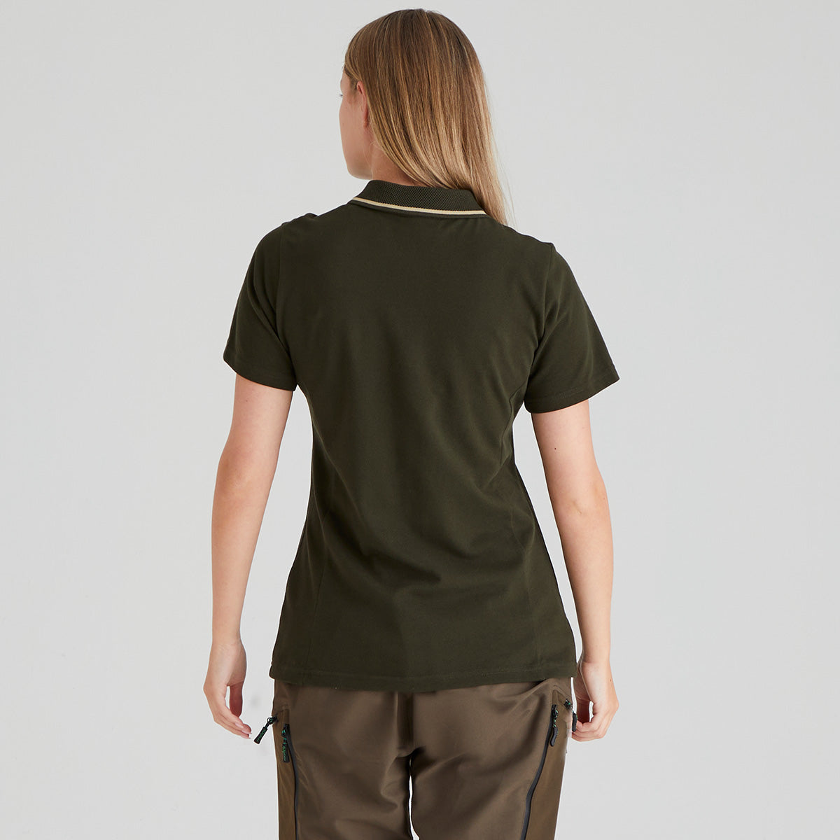 back view of person wearing a green polo shirt and brown pants on a light grey background