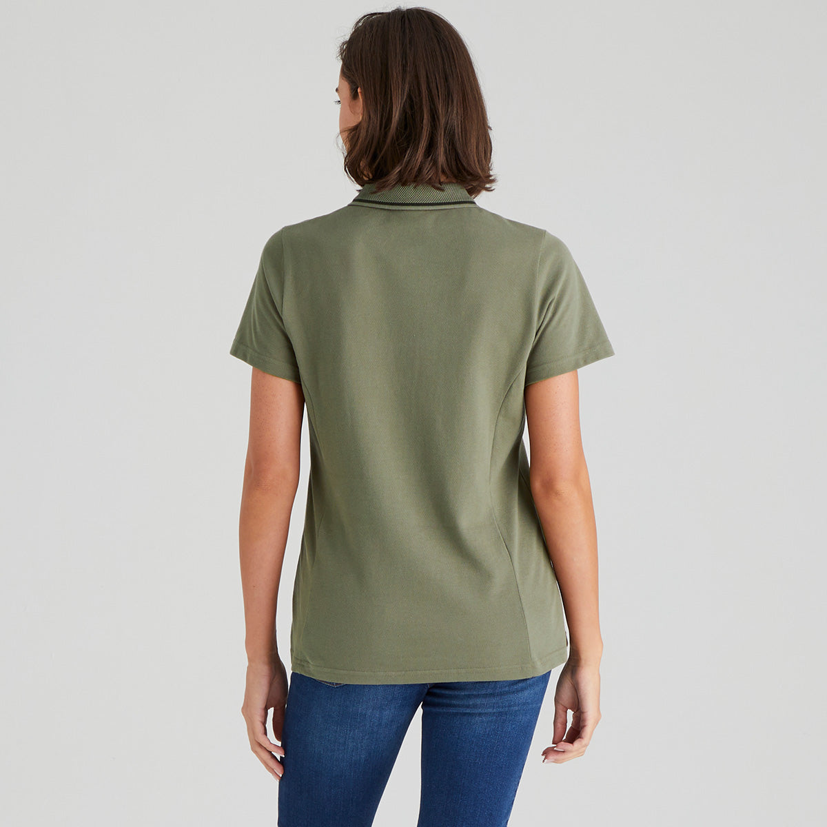 back view from person wearing a green polo shirt and blue jeans on a plain background