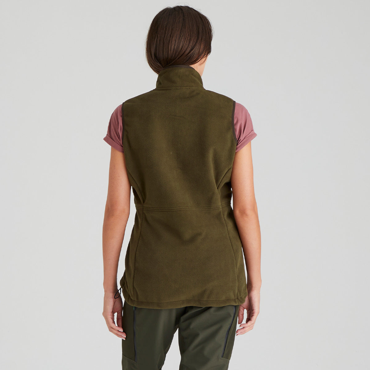 back view of person wearing a green vest over a pink shirt on a light grey background
