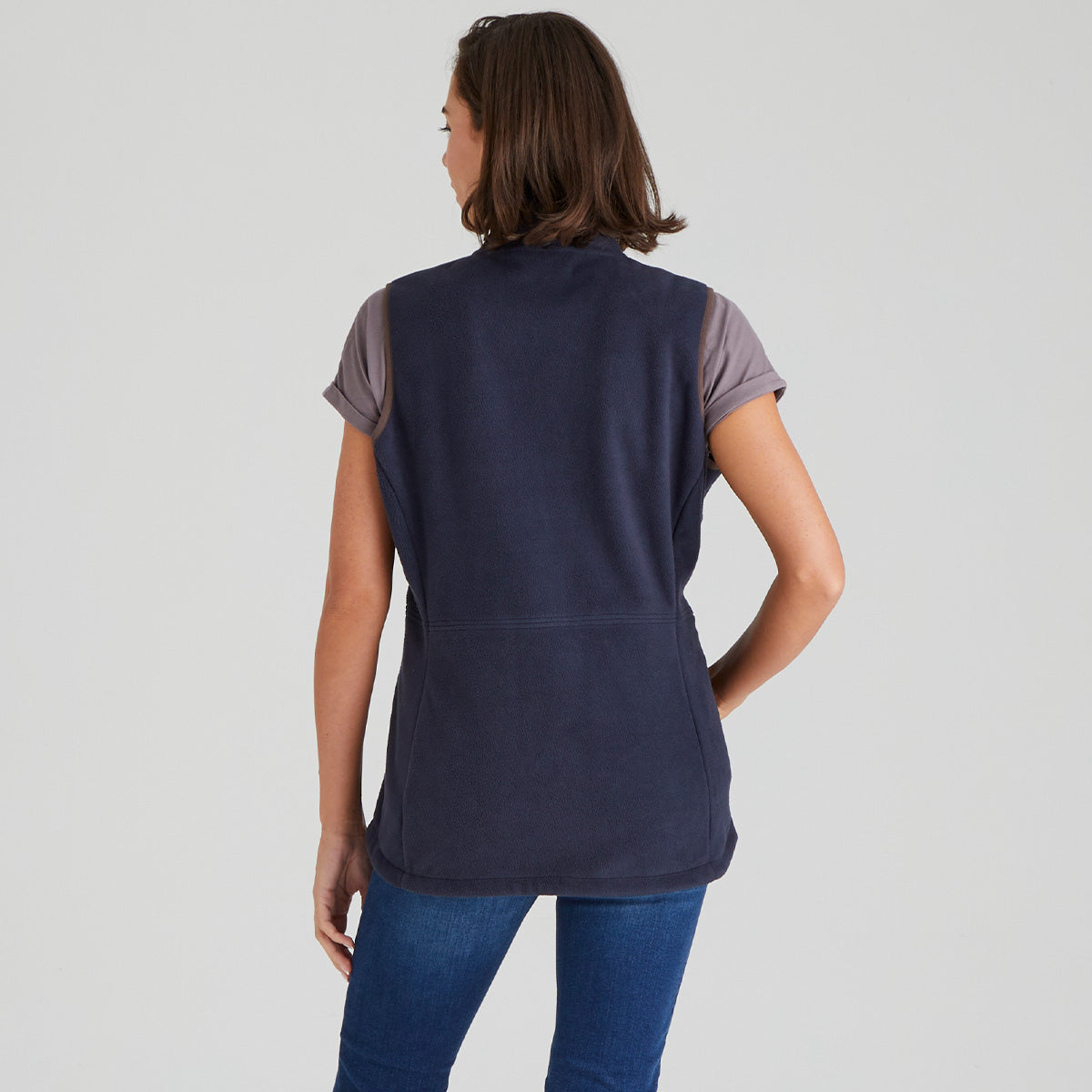 back view of woman wearing a navy sleeveless top with grey sleeves on a light grey background