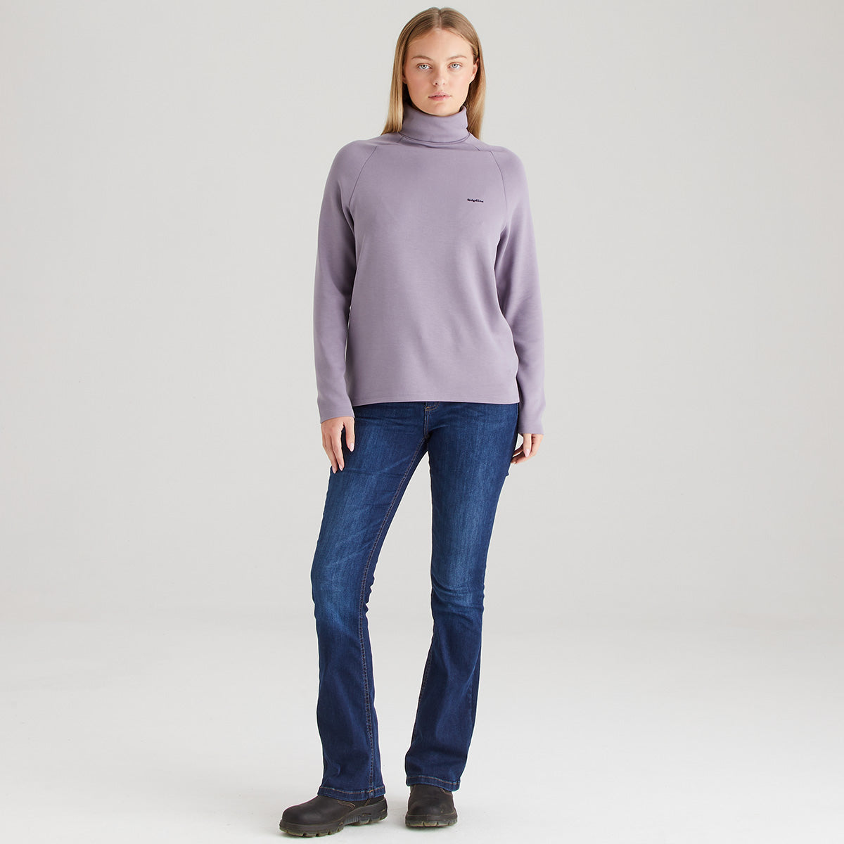 Person wearing a light purple turtleneck sweater and blue jeans on a white background