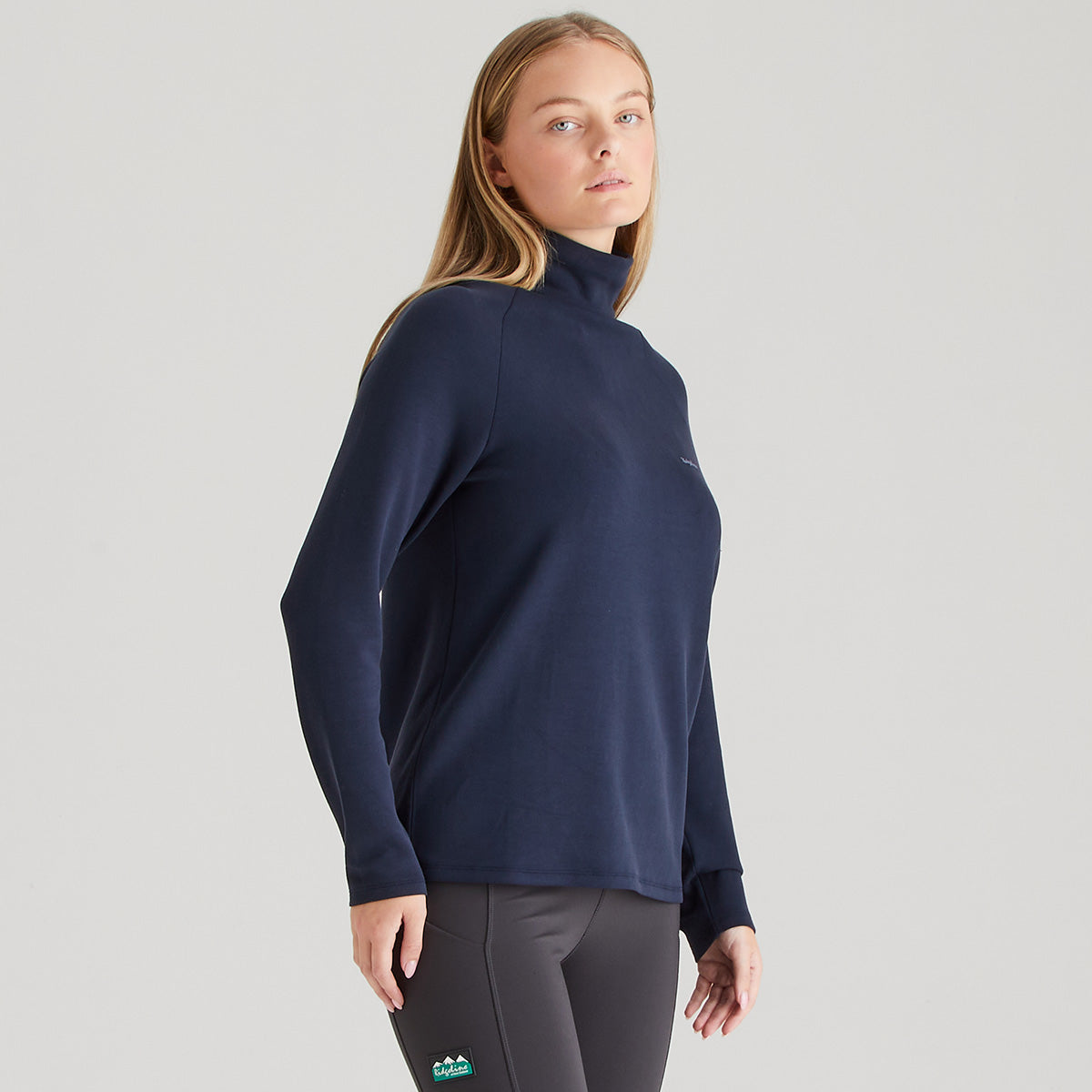 Woman wearing a navy long-sleeve top on a light gray background