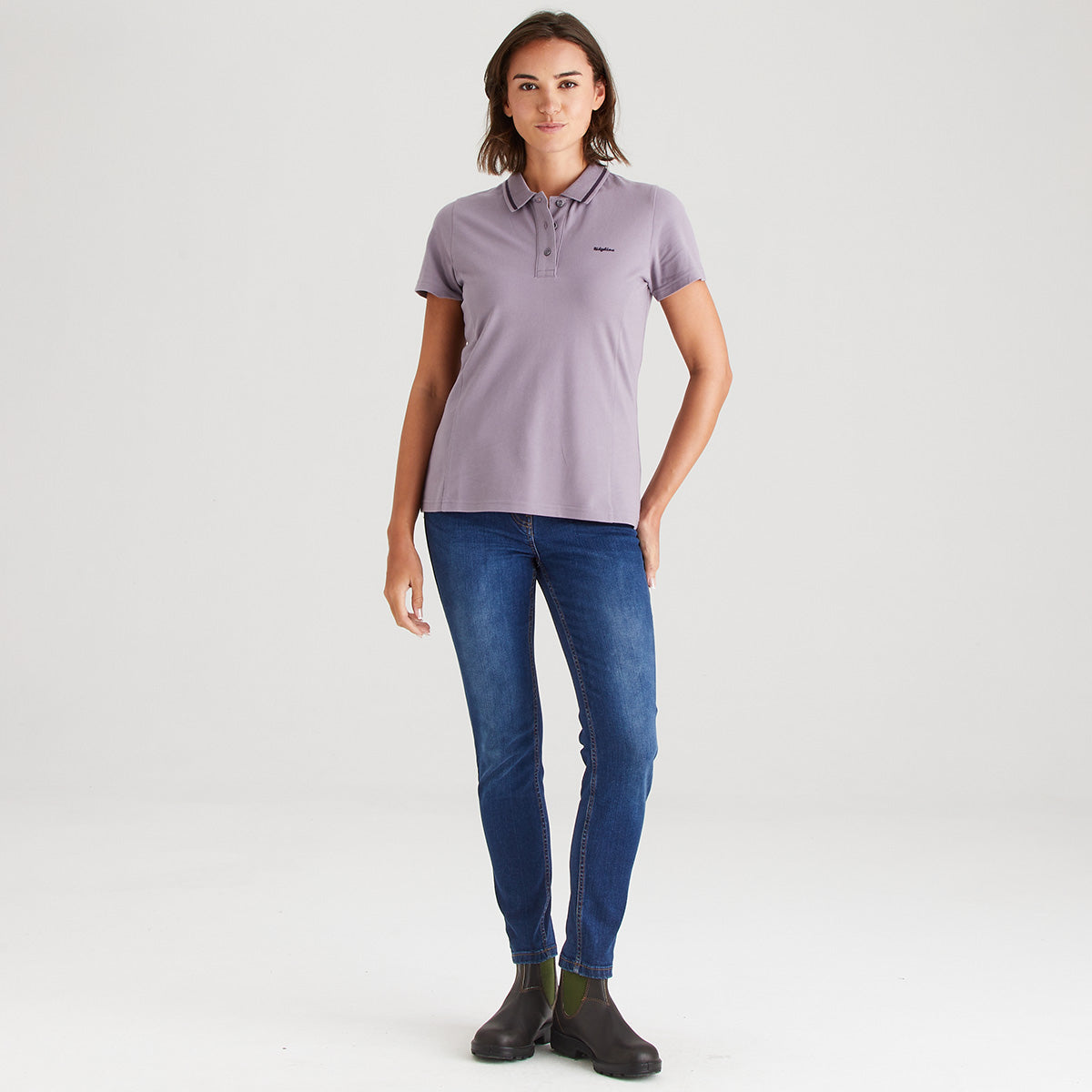 Woman wearing a purple polo shirt and blue jeans on a white background
