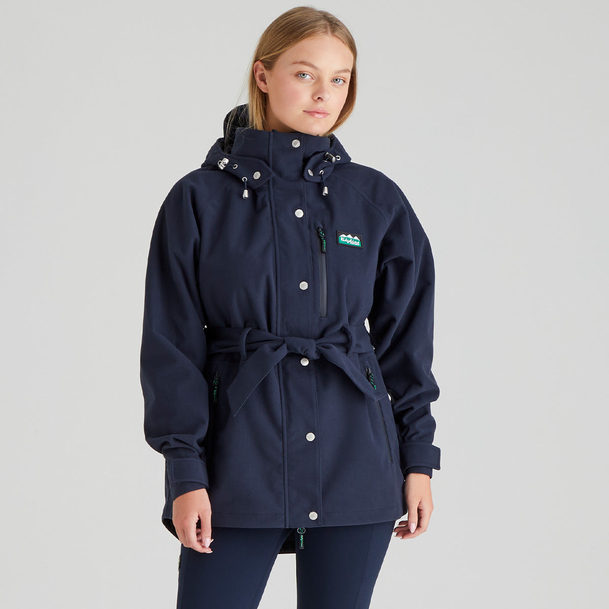 Woman wearing a navy blue waterproof raincoat without fur with a Ridgeline Clothing brand logo on a grey background