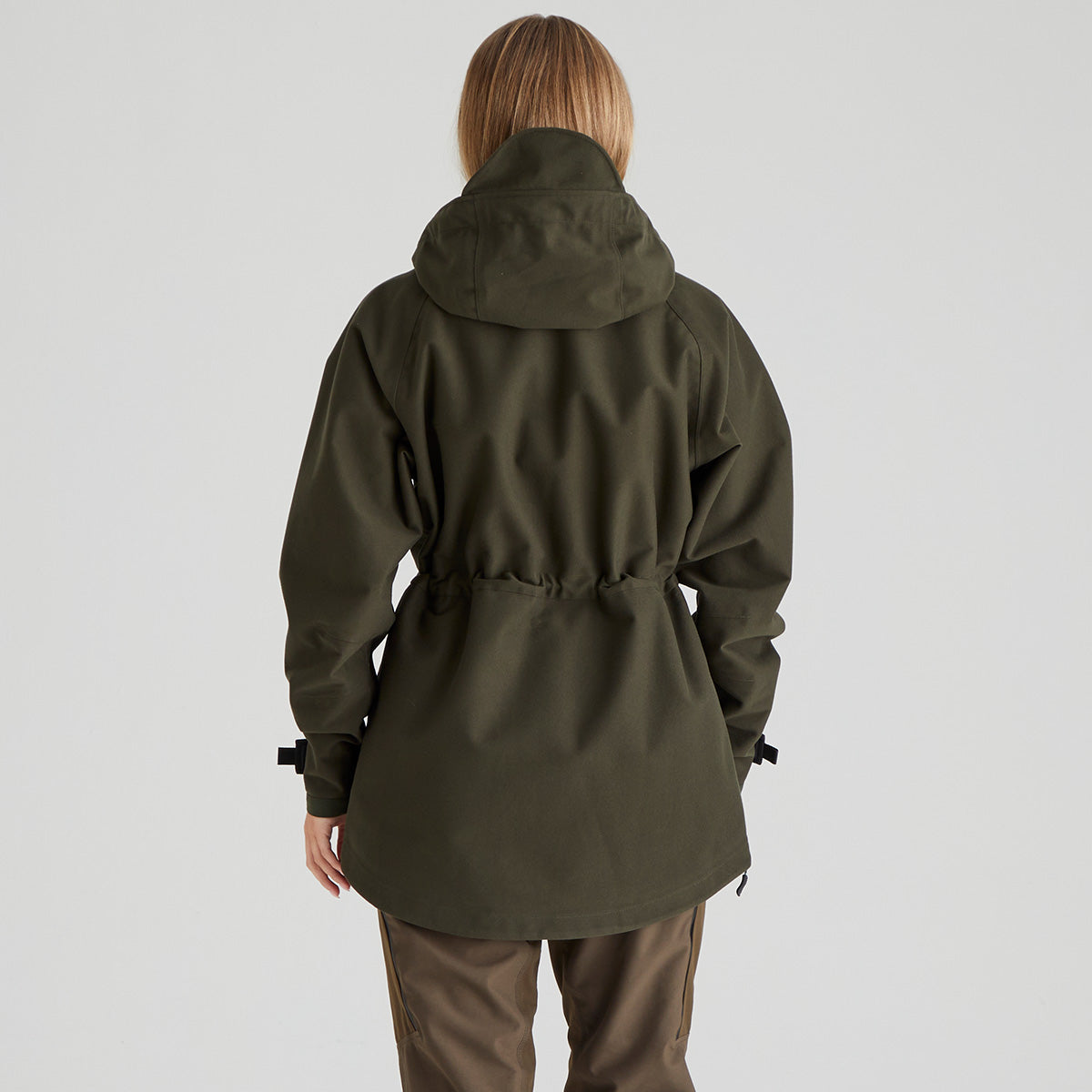 Back view of woman wearing a green hooded jacket on a plain background