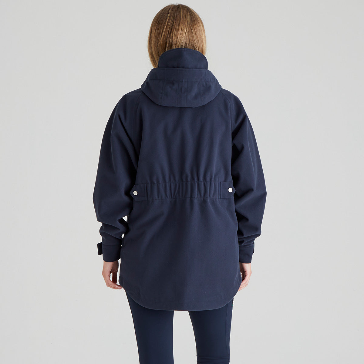 back view of Navy parka waterproof coat without fur hood worn by a person on a light grey background