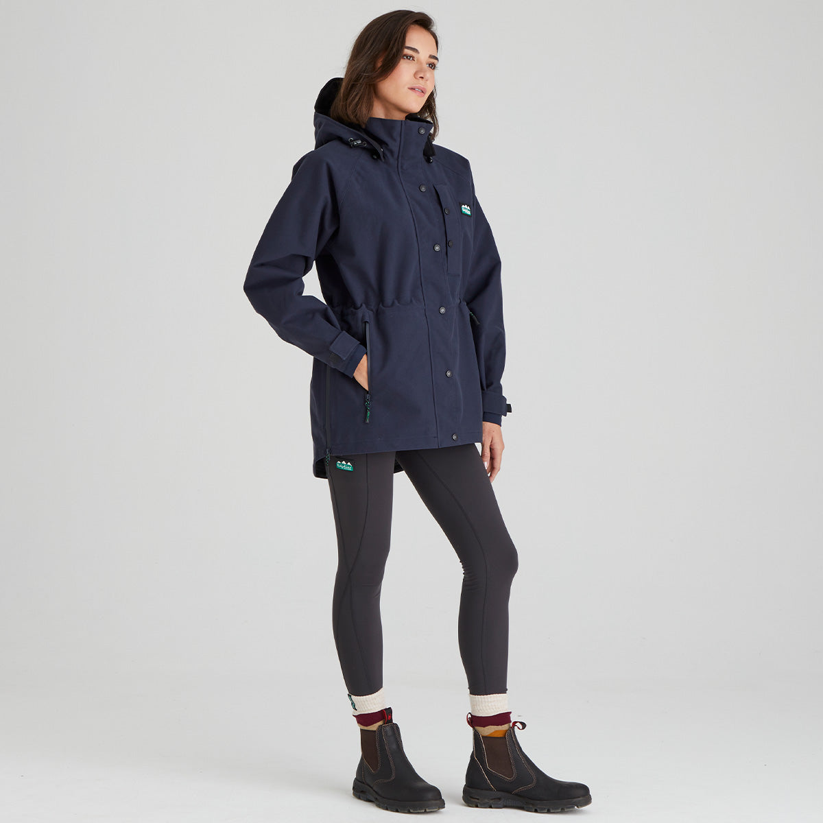 Woman wearing a navy raincoat on a light gray background