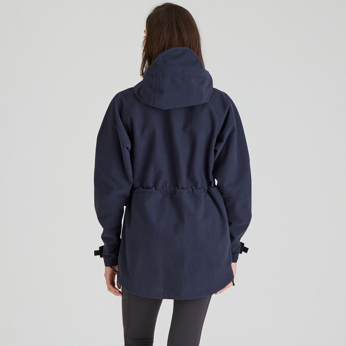 Back view of a person wearing a navy blue hooded jacket on a light grey background