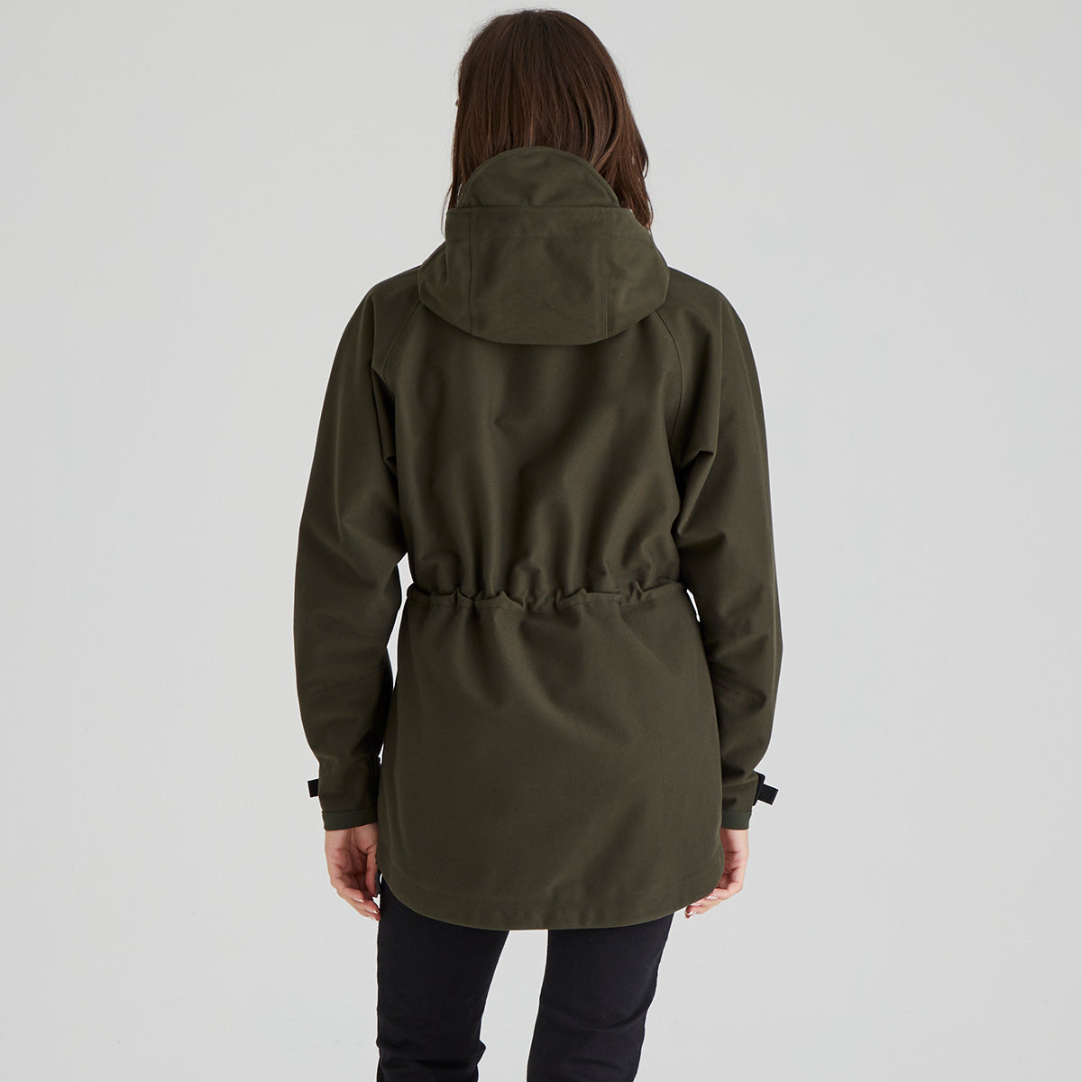 back view of woman wearing a green raincoat on a plain background