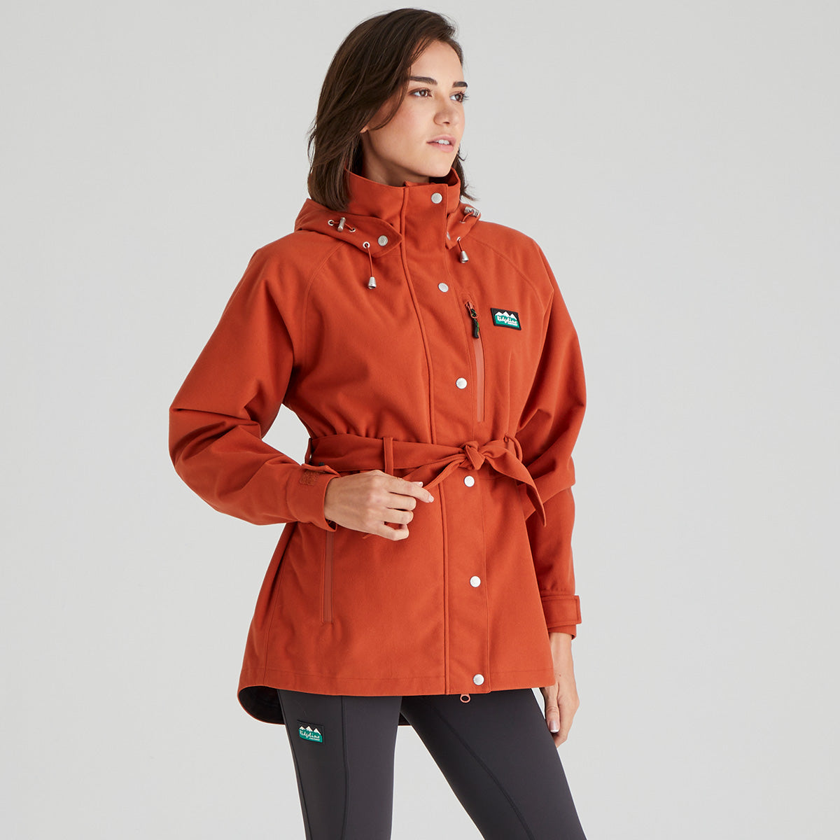 Woman wearing an orange raincoat with a brand logo on a gray background