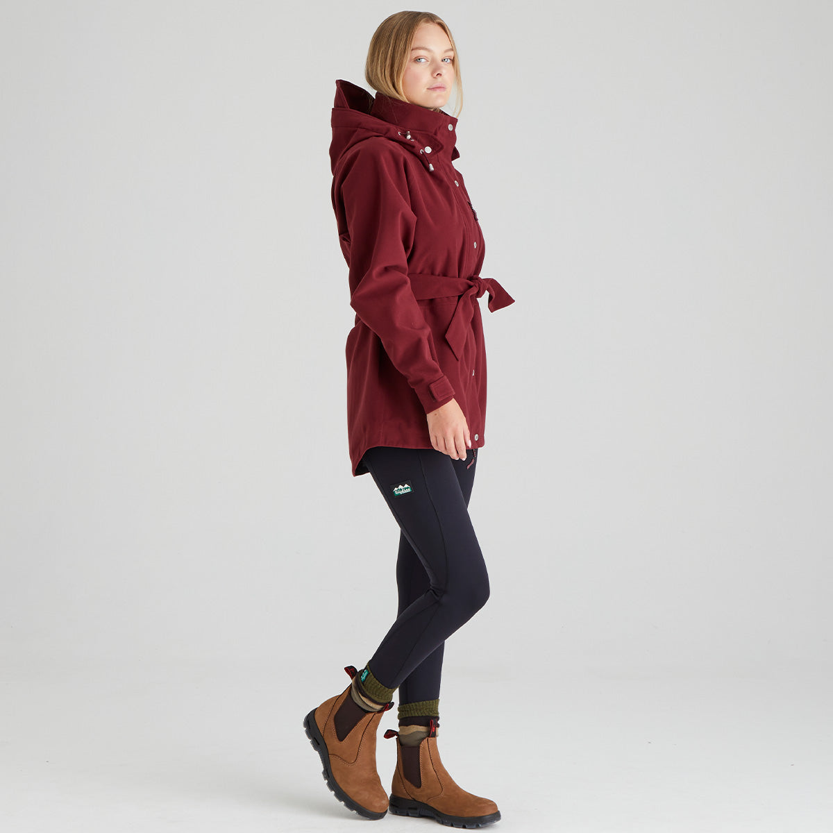 Person wearing a red raincoat, black pants, and brown boots on a white background