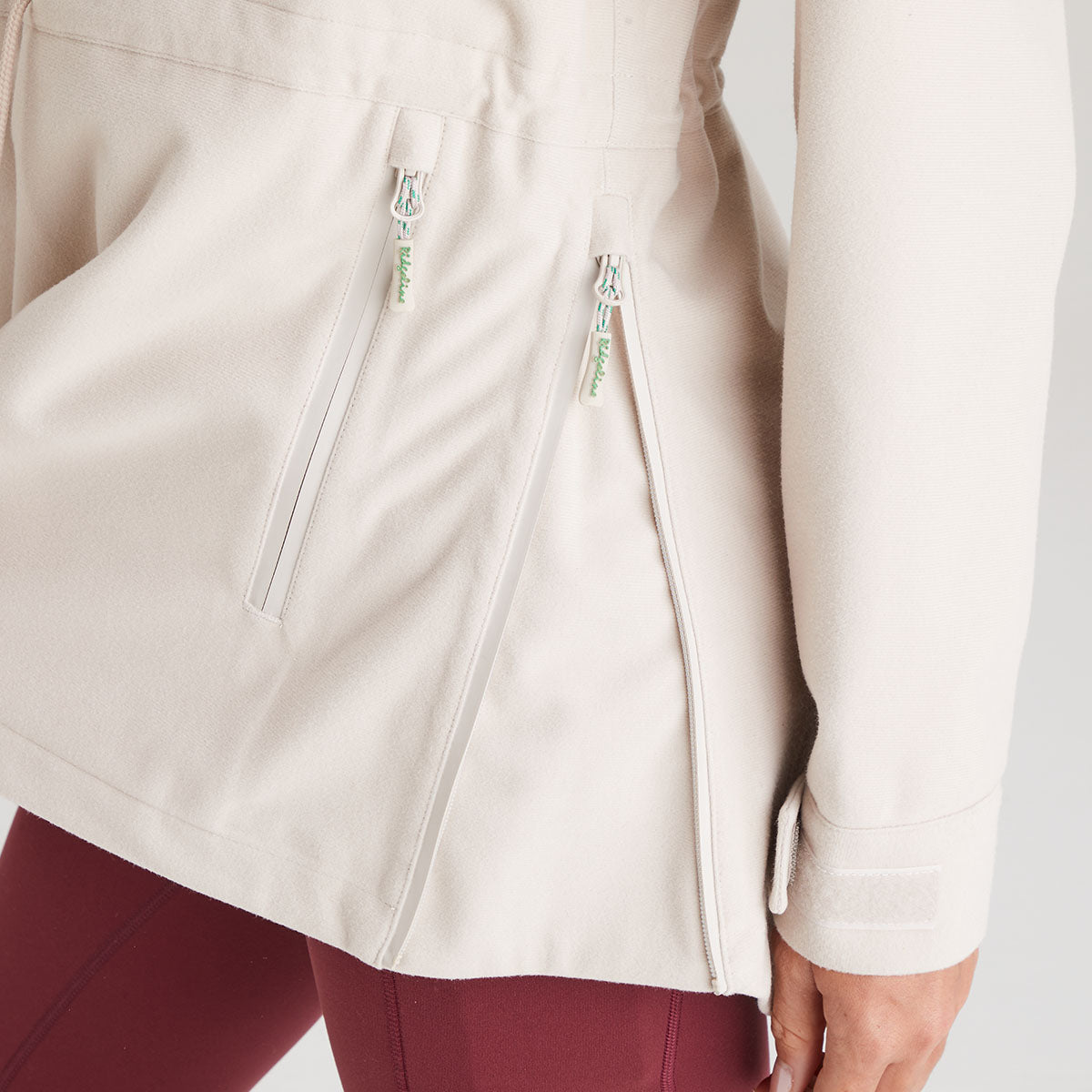Close-up of a cream jacket with zippers on a white background