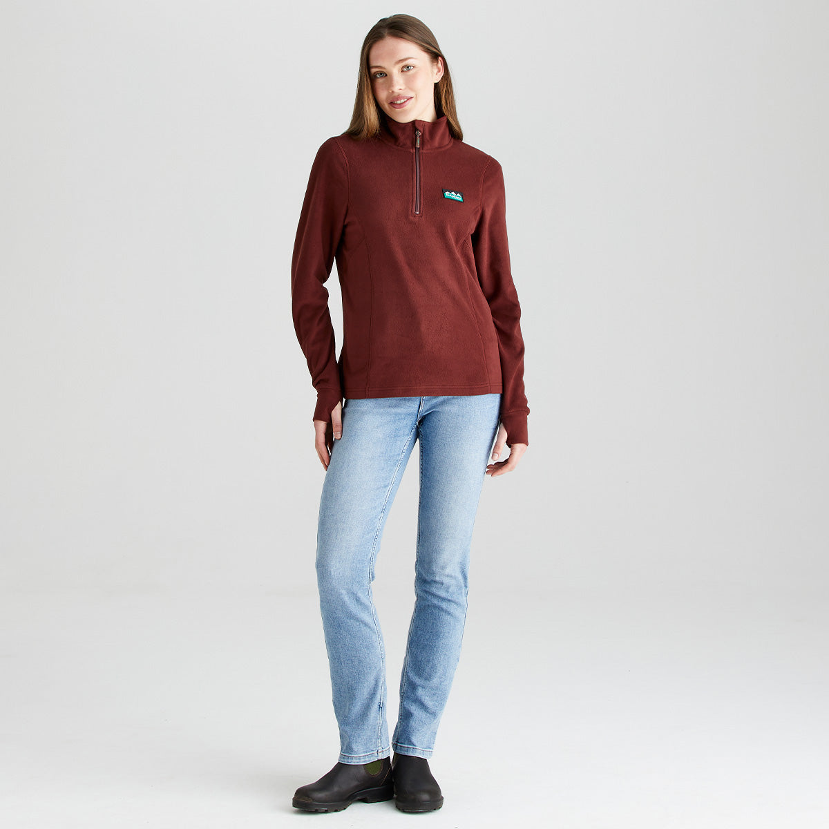 Burgundy half zip fleece pullover, front view, worn with light blue jeans and ankle boots.