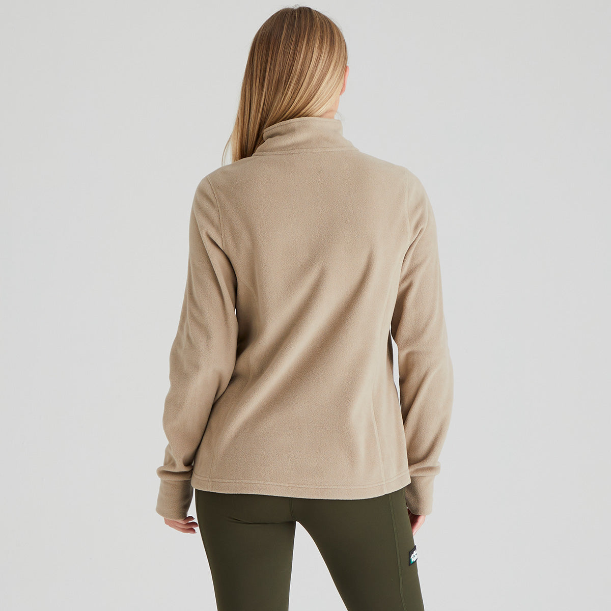 Back of person wearing a beige long-sleeve shirt on a plain background