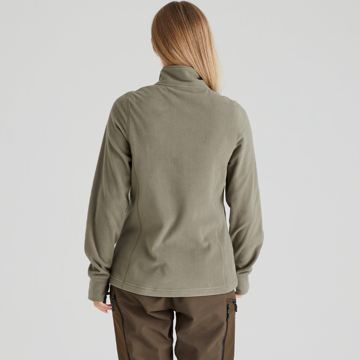 back of person wearing a green fleece jacket and brown pants on a light grey background