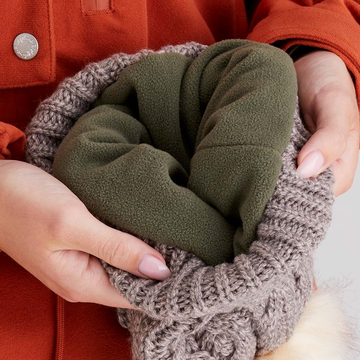 Green knitted item held by a person wearing an orange coat.