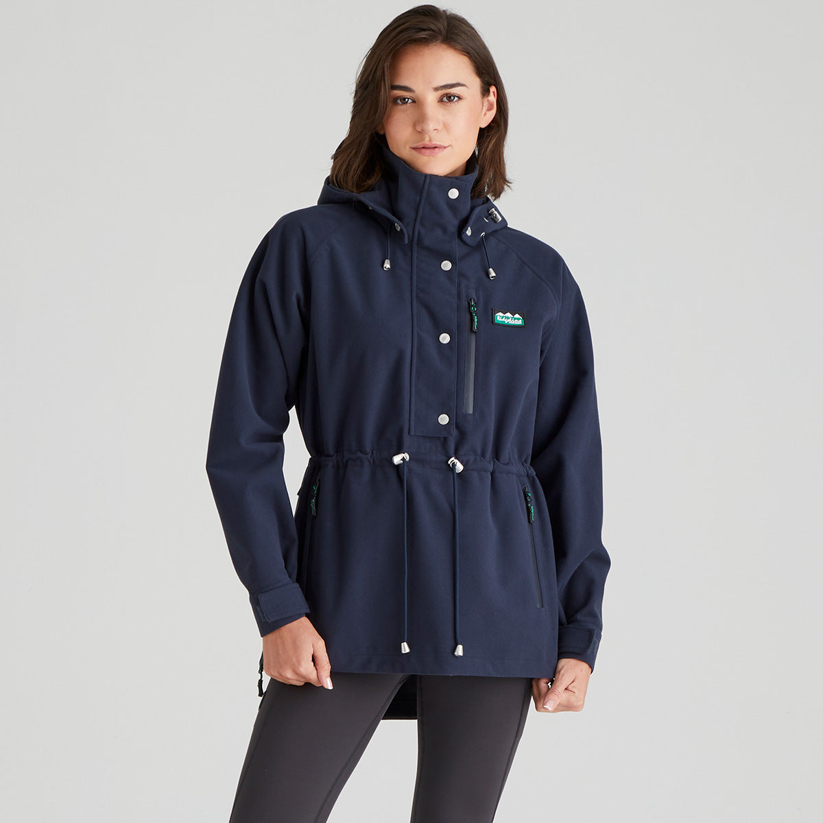Woman wearing a navy blue raincoat with a brand logo on a grey background