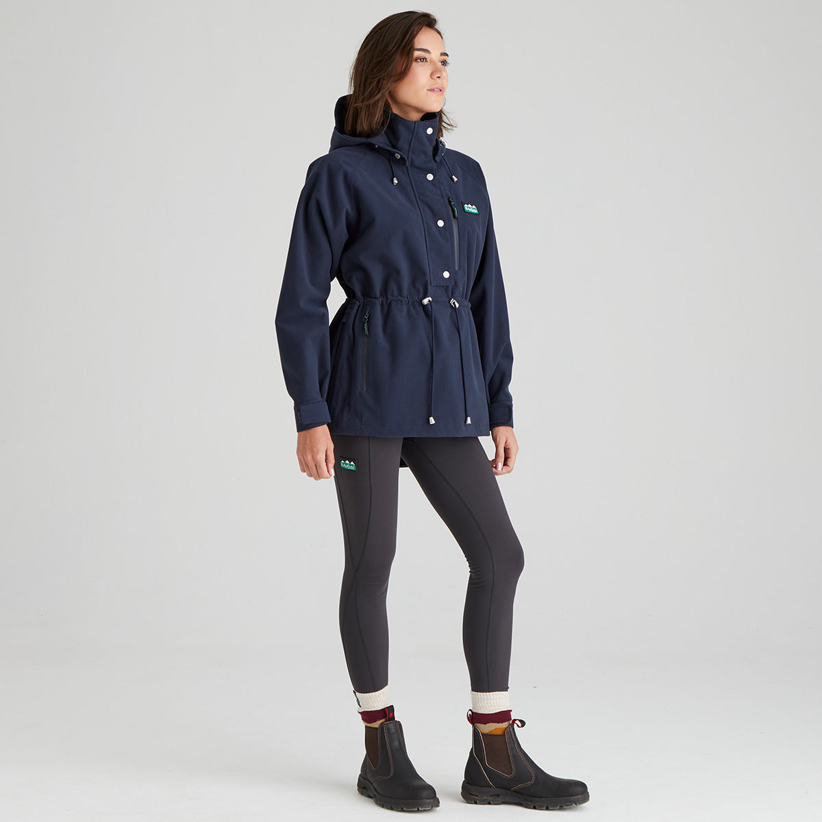 Person wearing a navy blue raincoat with a hood on a light grey background