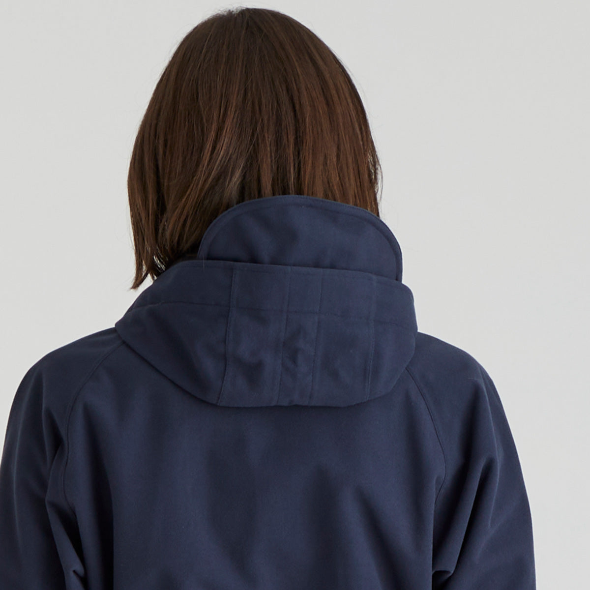 Person wearing a navy blue jacket with a plain background