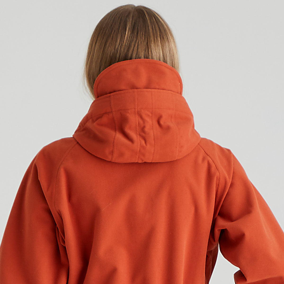 Person wearing an orange jacket on a plain background