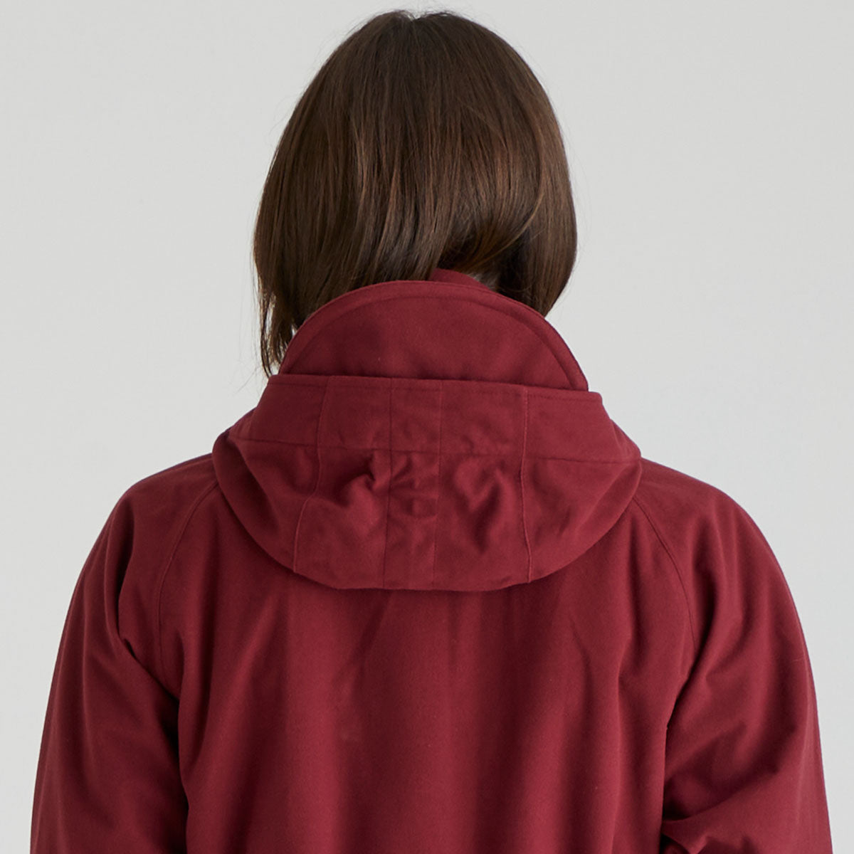 Person wearing a red jacket with a hood on a plain background