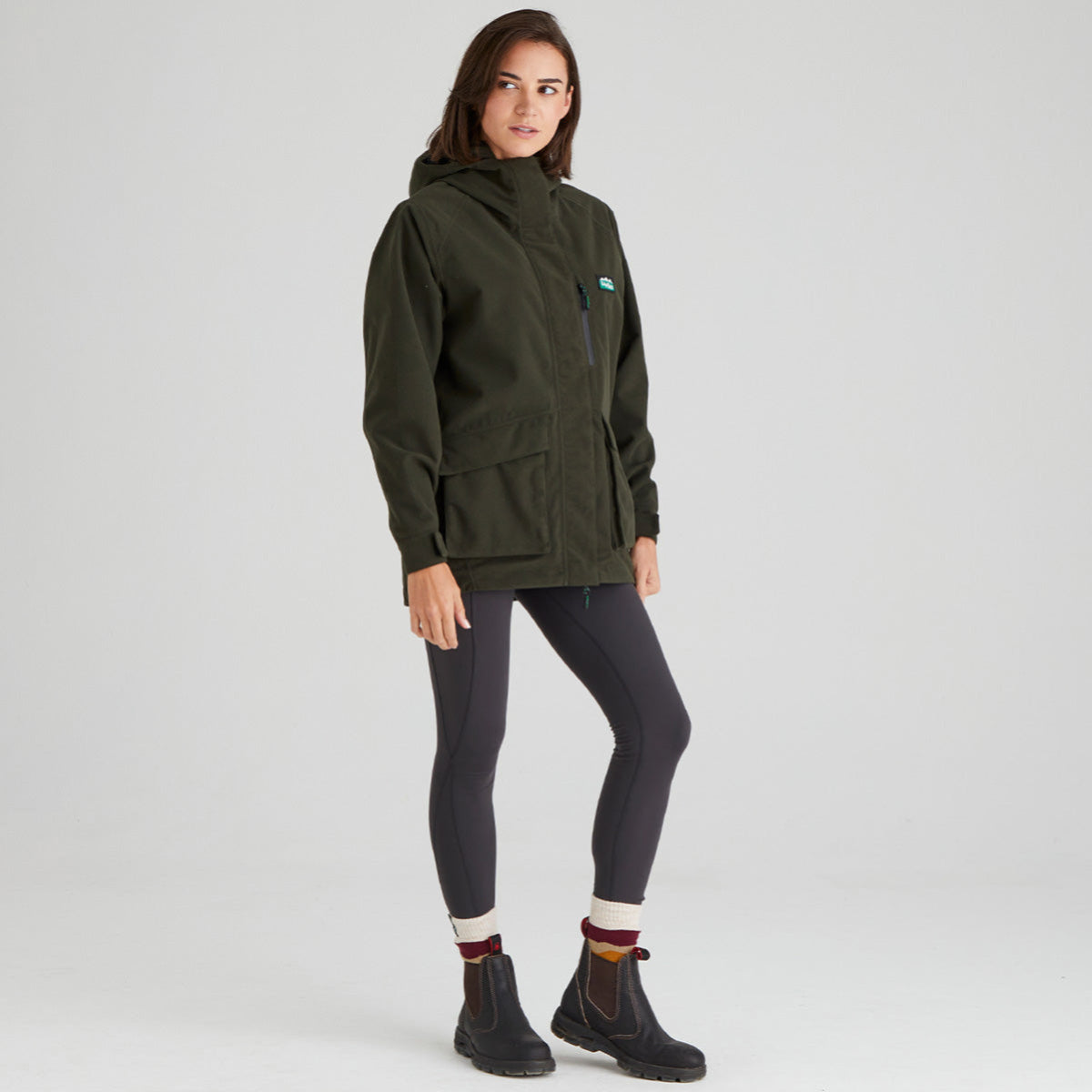 Person wearing a green hooded jacket on a light grey background