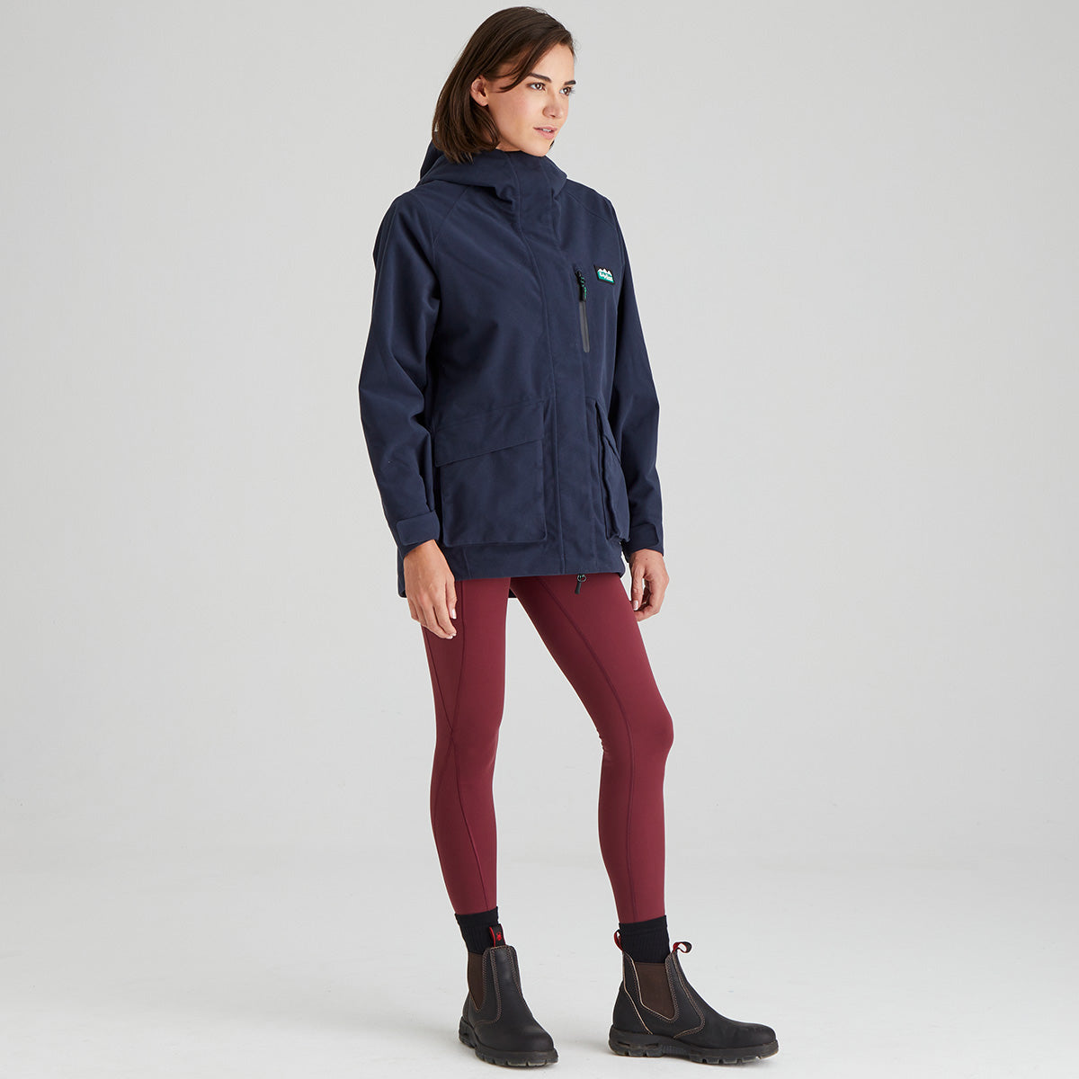 Person wearing a navy jacket and maroon pants on a light grey background