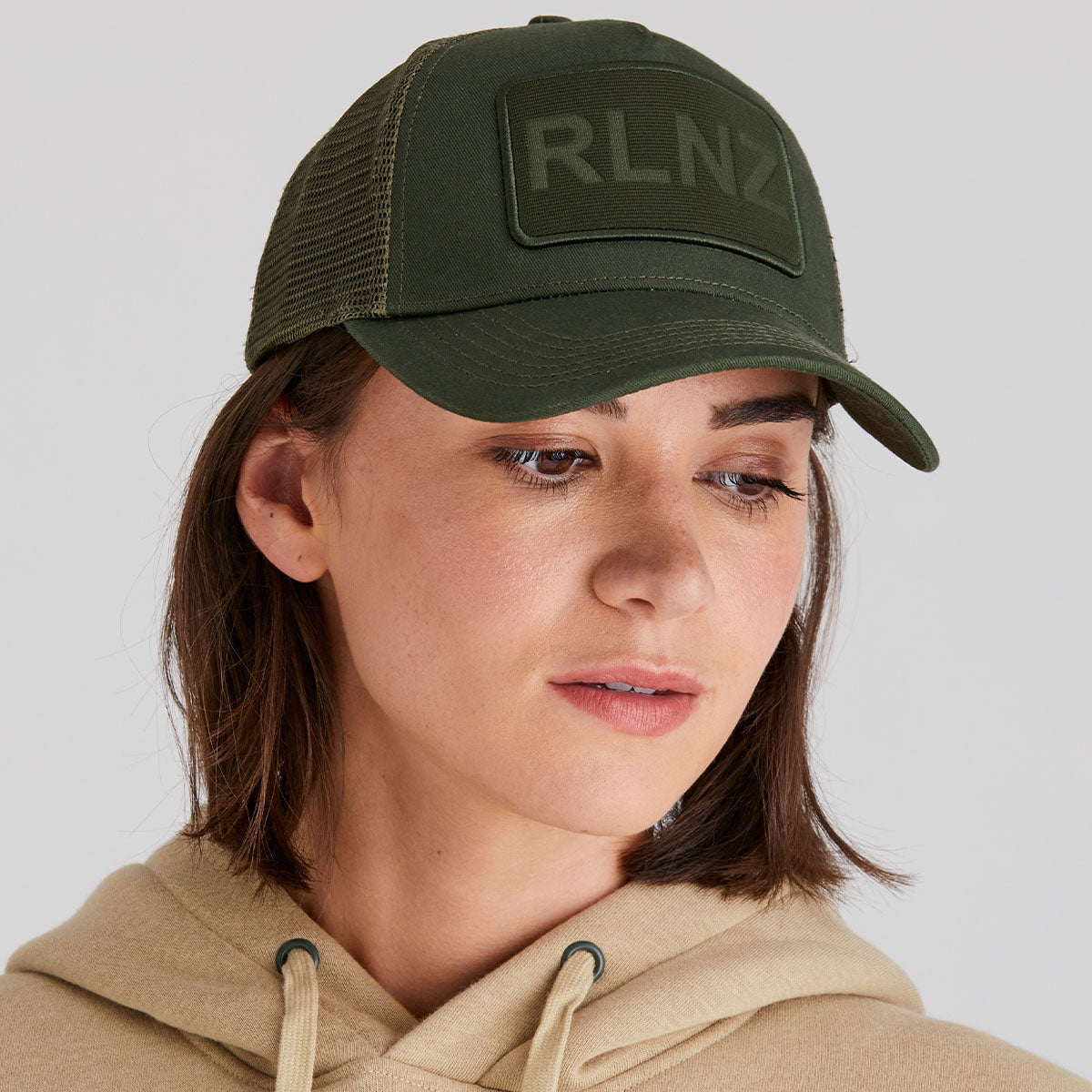 Person wearing a green cap with 'RLNZ' logo on a plain background