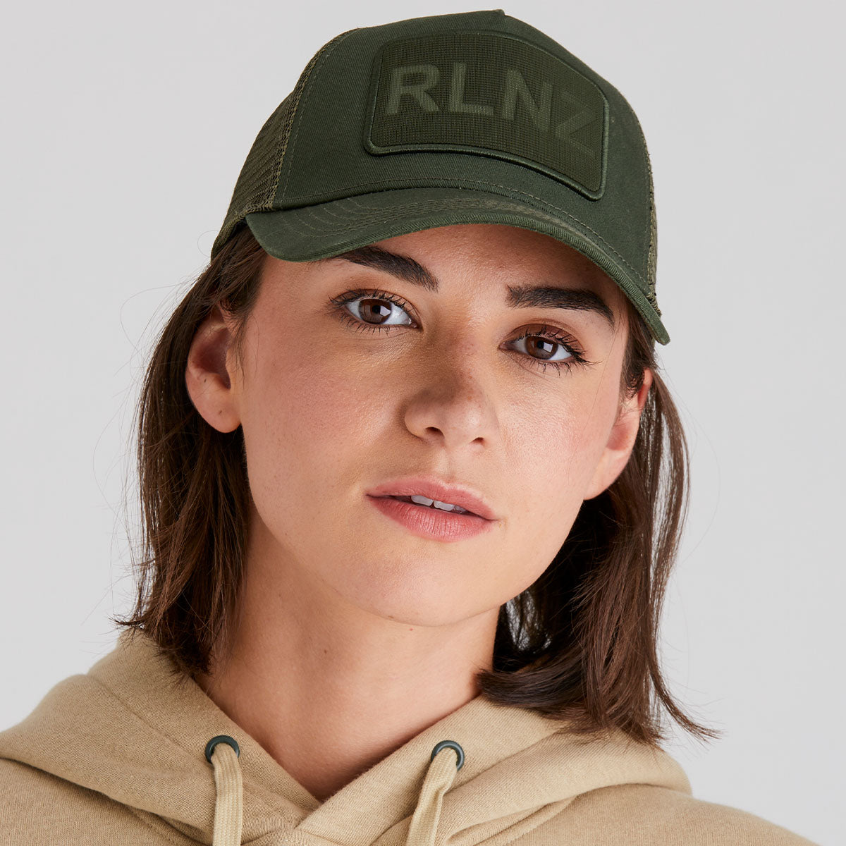 Person wearing a green cap with 'RLNZ' logo on a light grey background