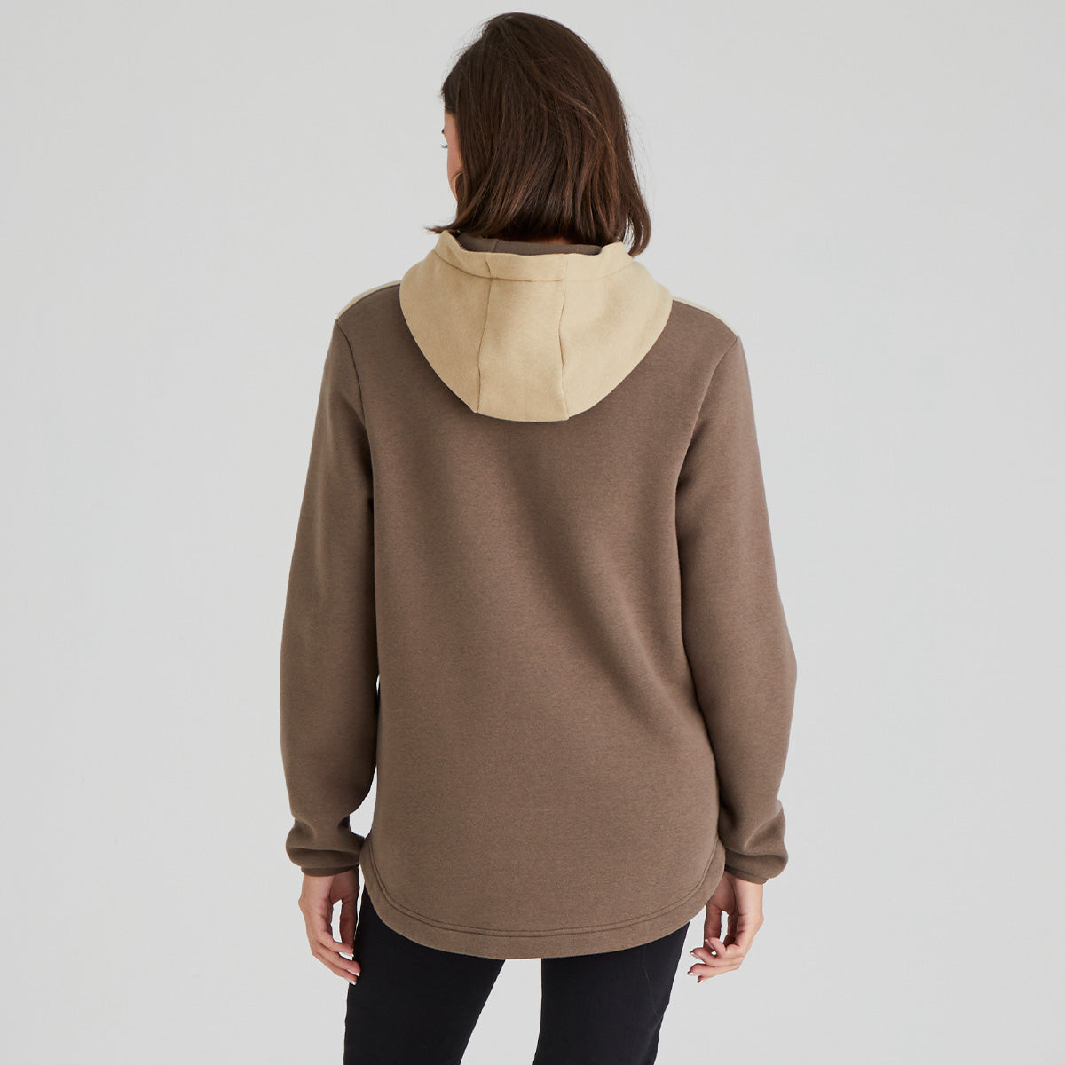 Person wearing a brown hoodie with beige hoodie on a plain background