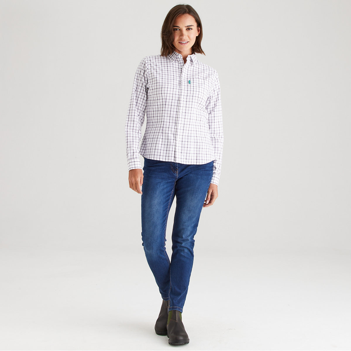 Woman wearing a checkered shirt and blue jeans on a white background