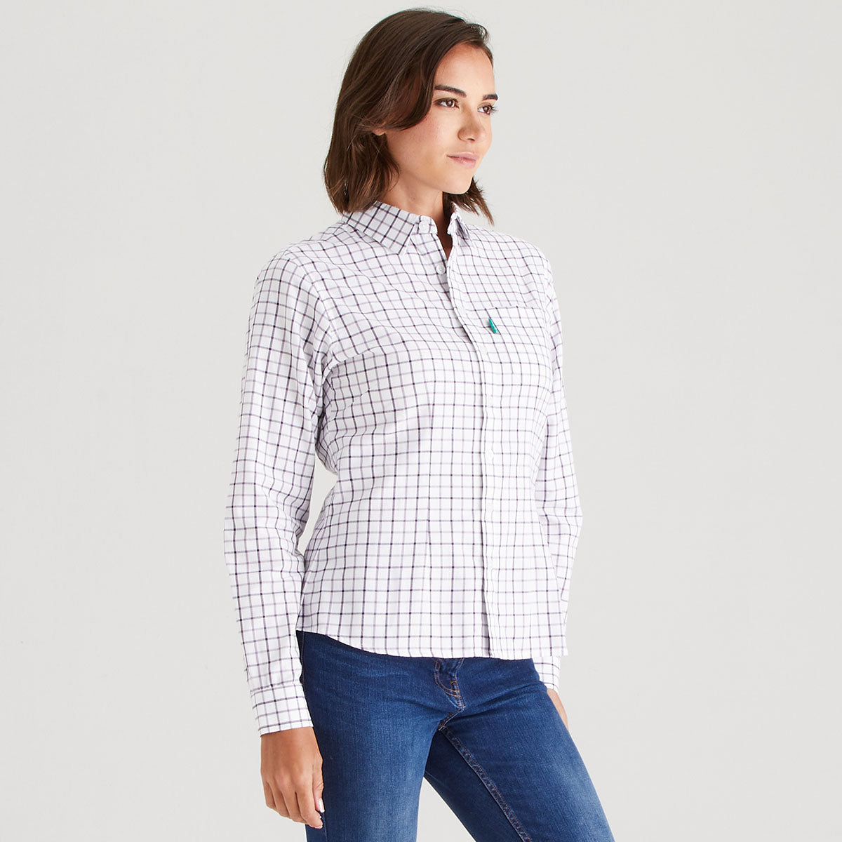 Woman wearing a checkered shirt and blue jeans on a gray background