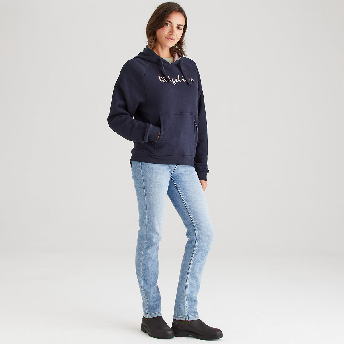 Person wearing a navy hoodie with text and light blue jeans on a white background