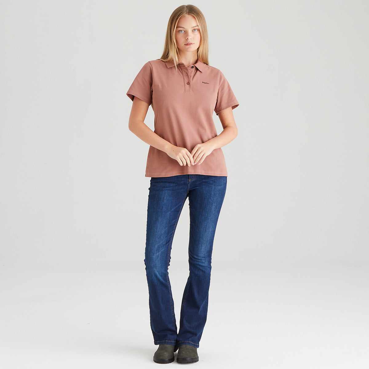 Woman wearing a pink polo shirt and blue jeans on a white background