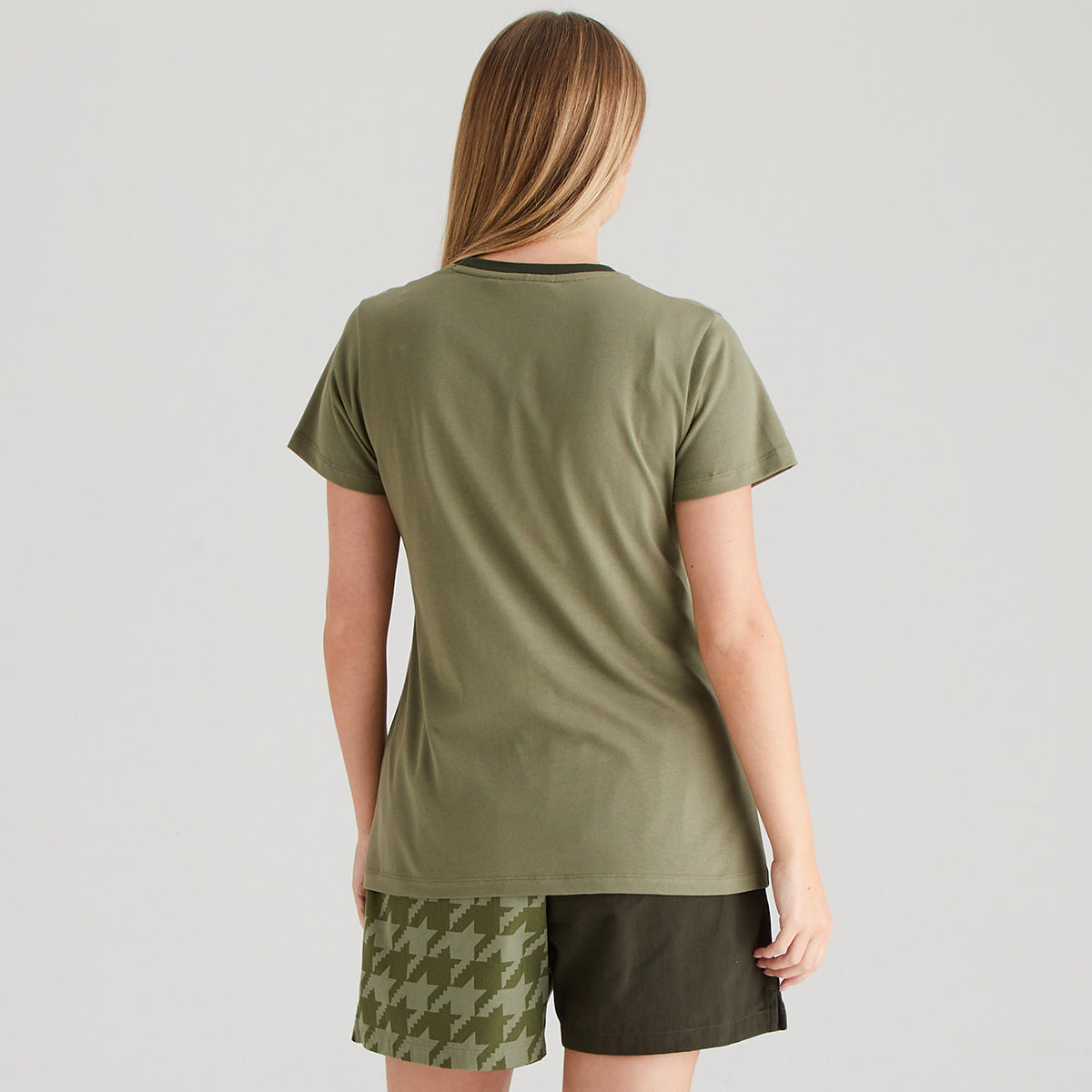 Person wearing an olive green t-shirt and shorts on a light gray background
