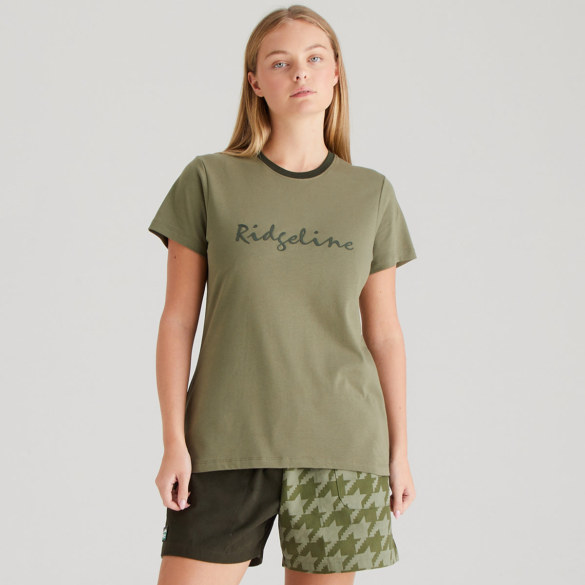 Woman wearing an olive green t-shirt with 'Ridgeline' branding on a gray background