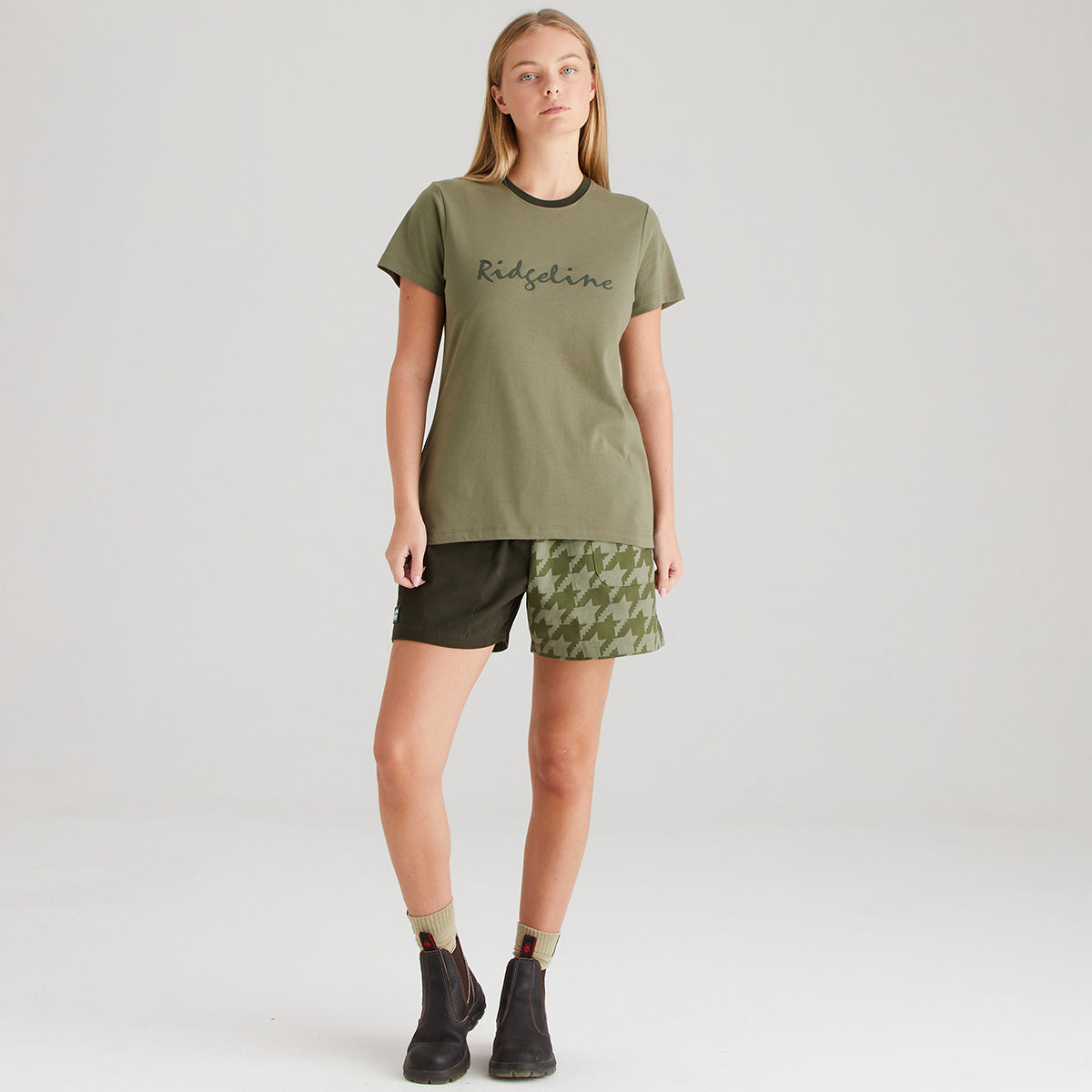 Woman wearing an olive green t-shirt and shorts on a white background