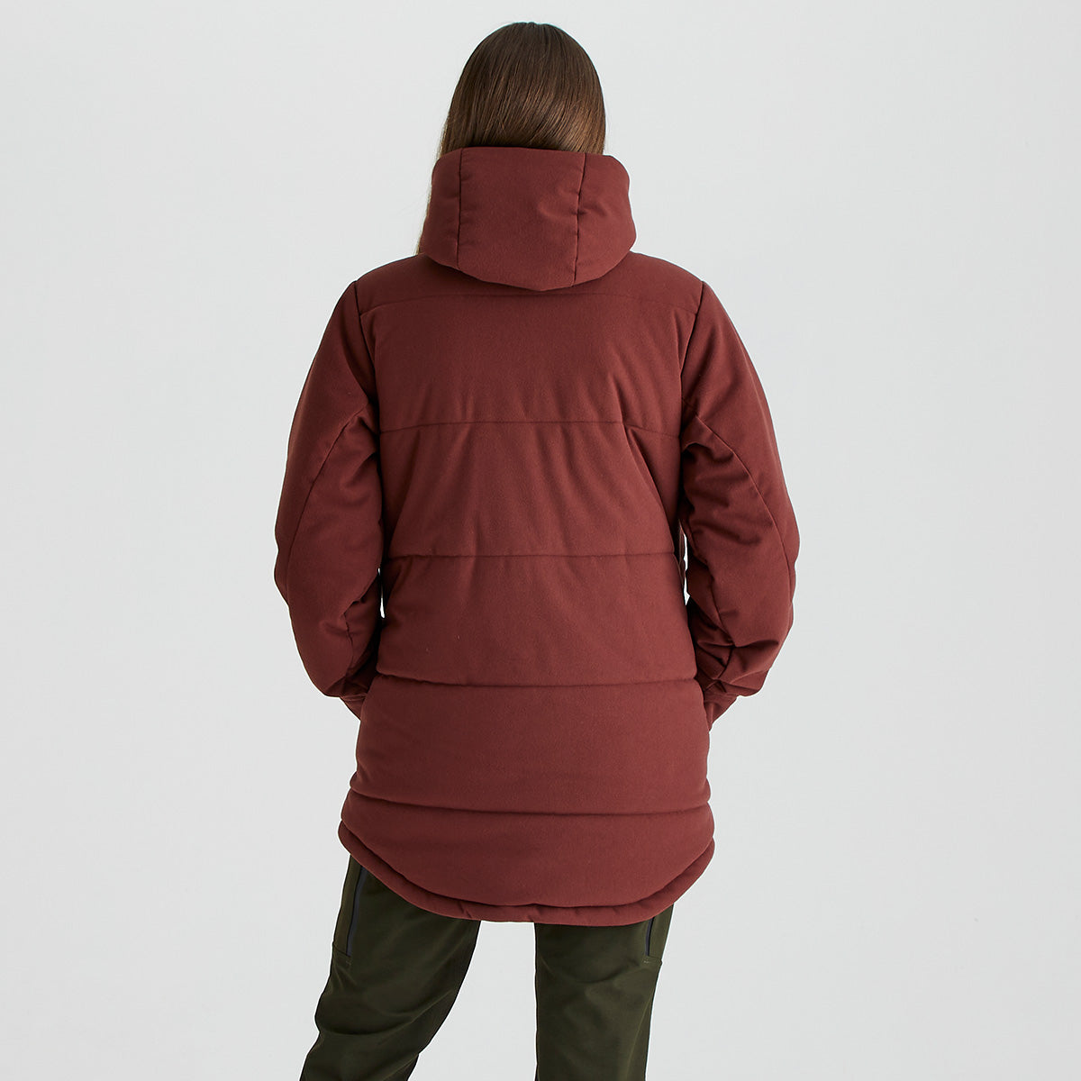 Rear view of a person wearing a Ridgeline burgundy insulated hooded jacket with a padded design and extended curved back hem, paired with olive trousers, shown against a light grey studio background.
