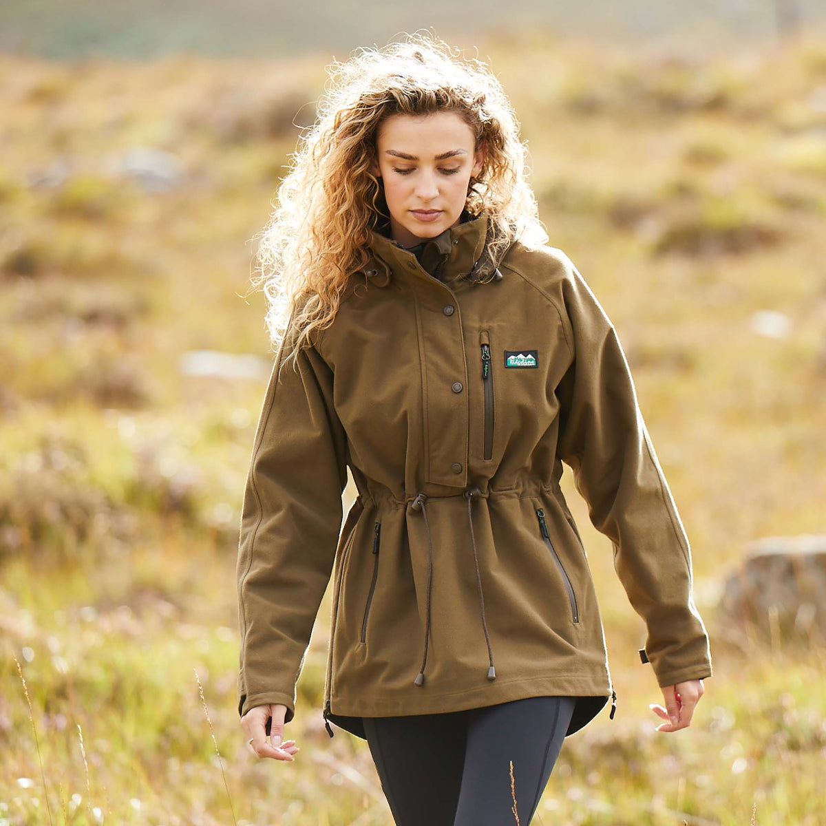 Woman wearing a A brown Monsoon II Classic Smock walking through an outdoor field