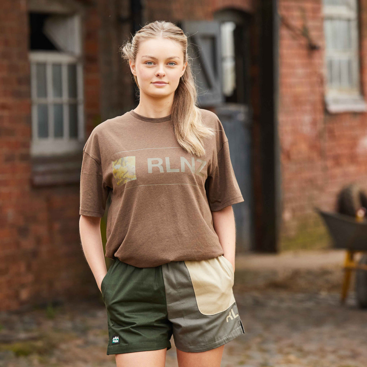 women wearing olive backslider shorts with a RLNZ t-shirt in brown. 