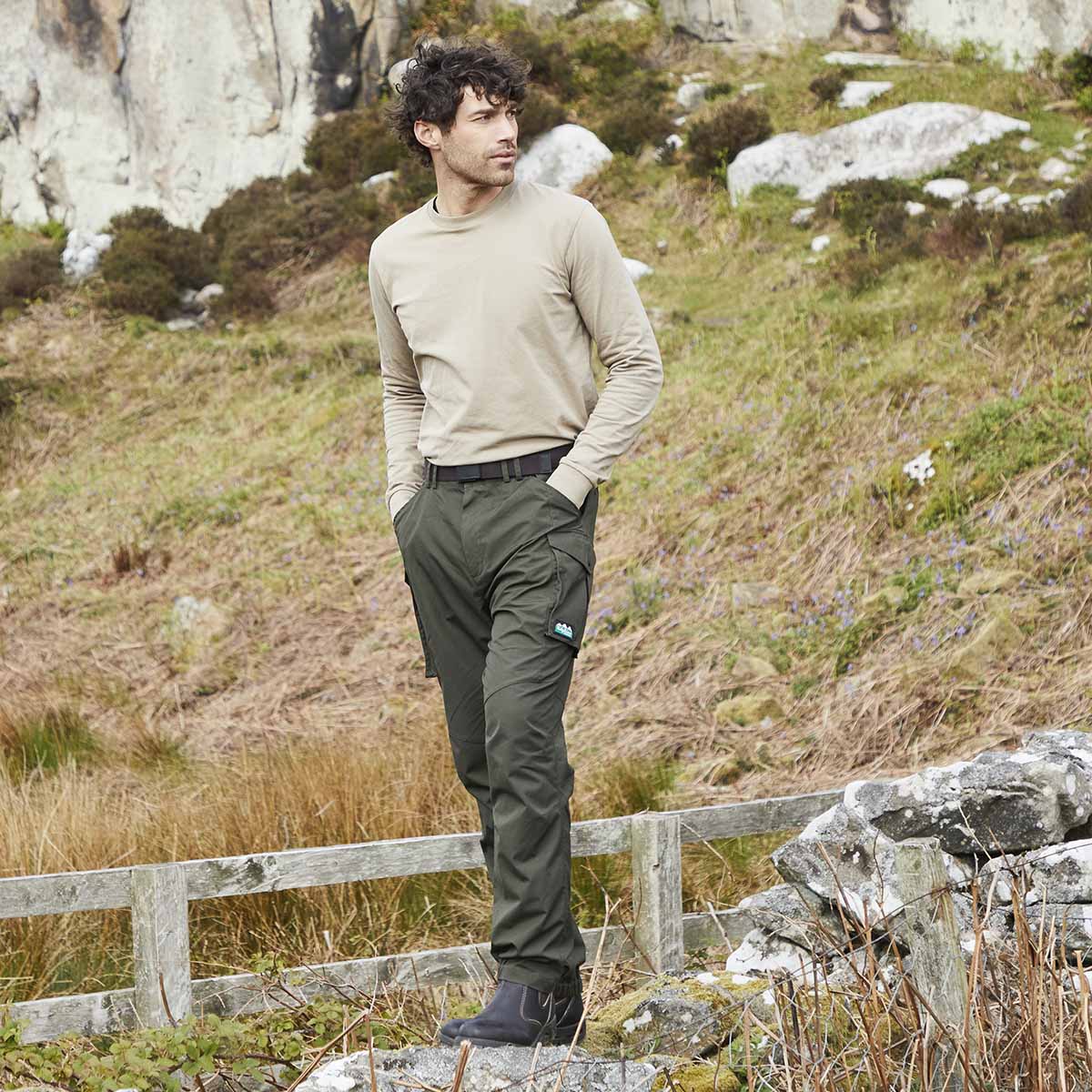 Ridgeline brown webbing belt with adjustable steel buckle, worn with green cargo trousers in outdoor setting