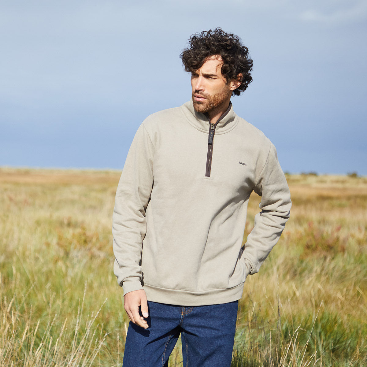 Man wearing a beige pullover in grass field 
