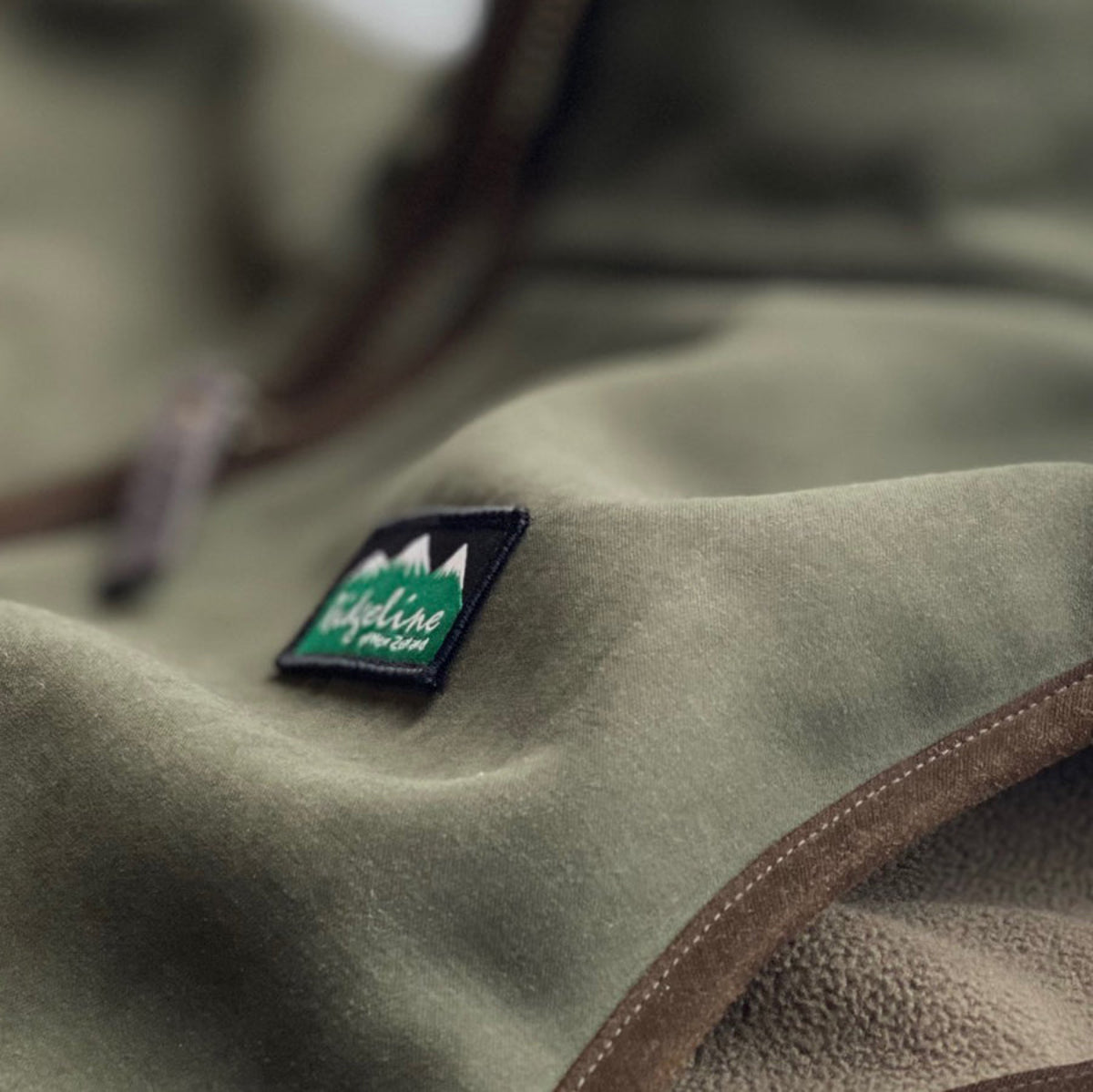 Close-up of a green jacket with a logo patch on a blurred background