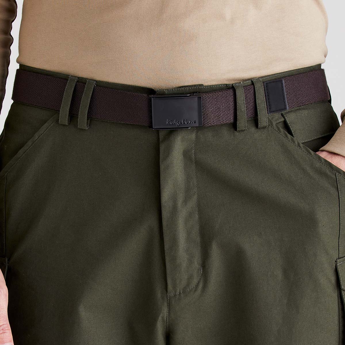 Brown woven fabric belt with black plaque buckle worn with trousers, close-up view.