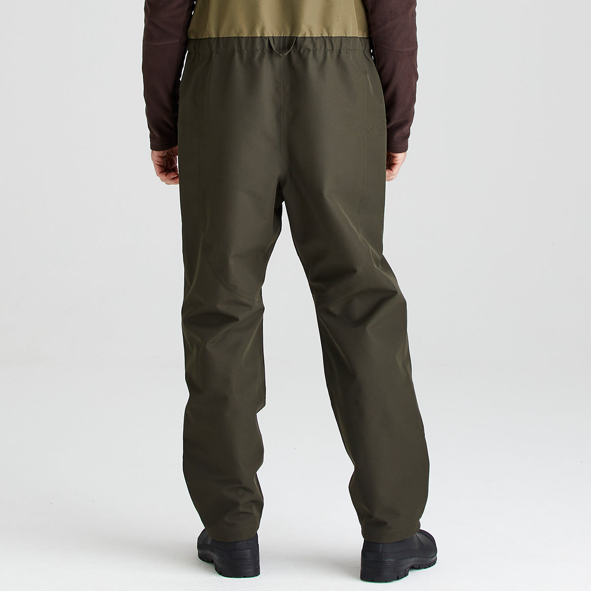 Person wearing olive green bib & brace on a white background