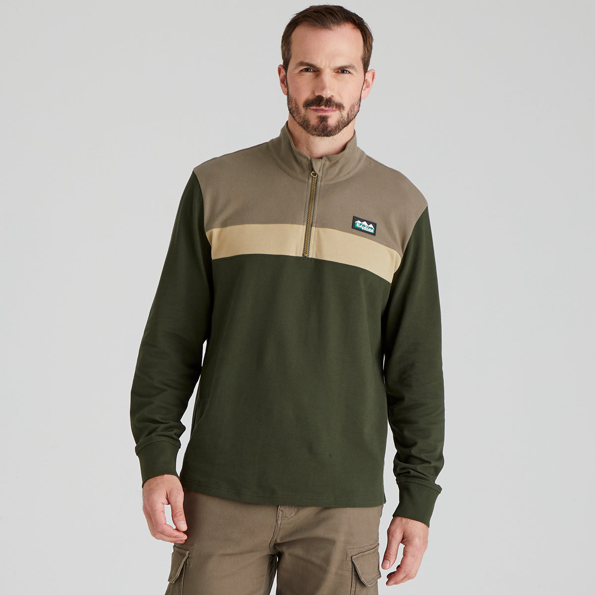 Man wearing a green and beige pullover with a visible Ridgeline Clothing brand logo on a grey background