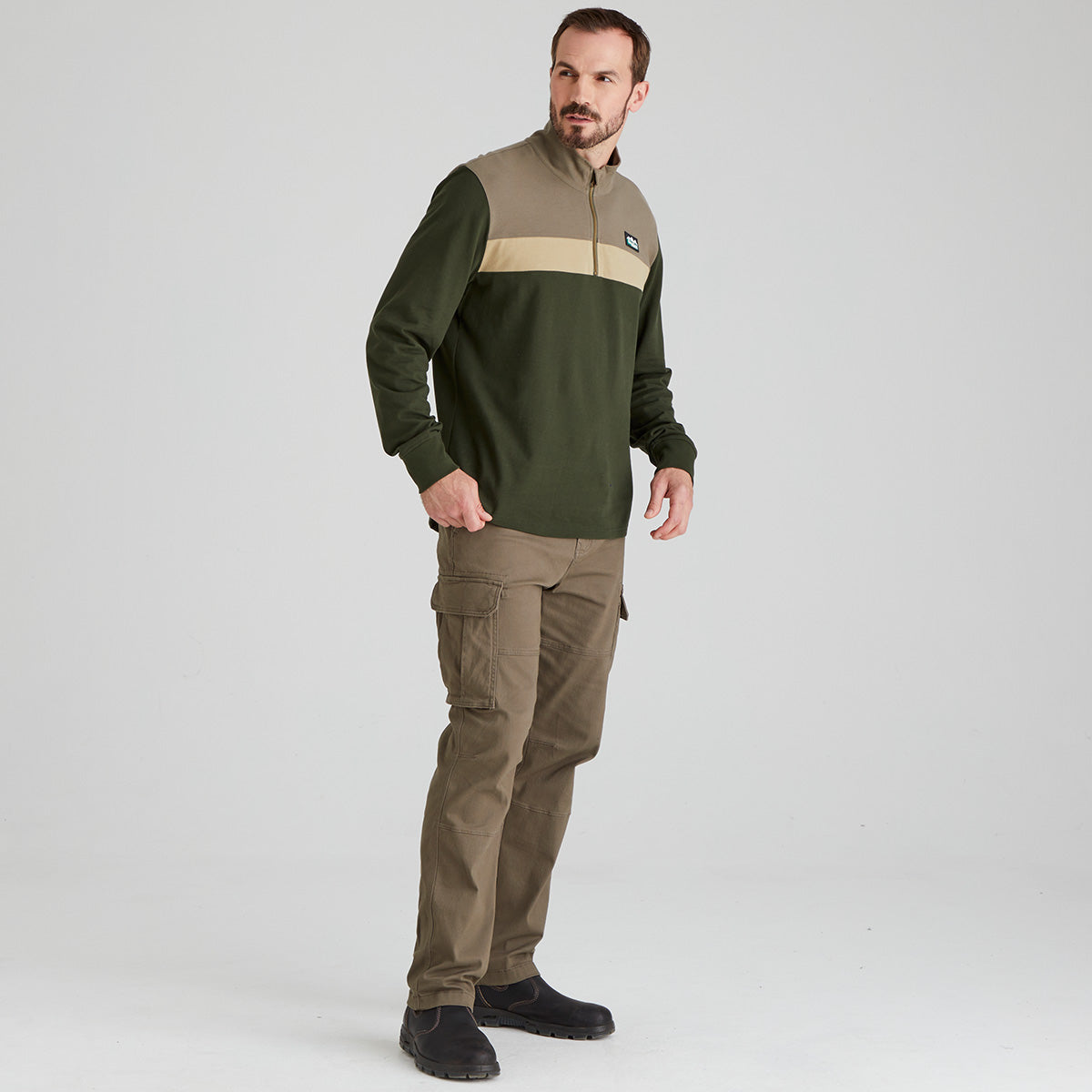 Man wearing a green and beige pullover with cargo pants on a white background