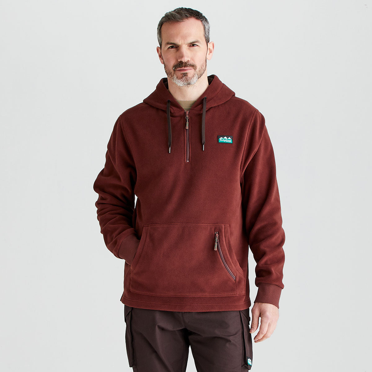 Man wearing a maroon hoodie with a logo on a light gray background