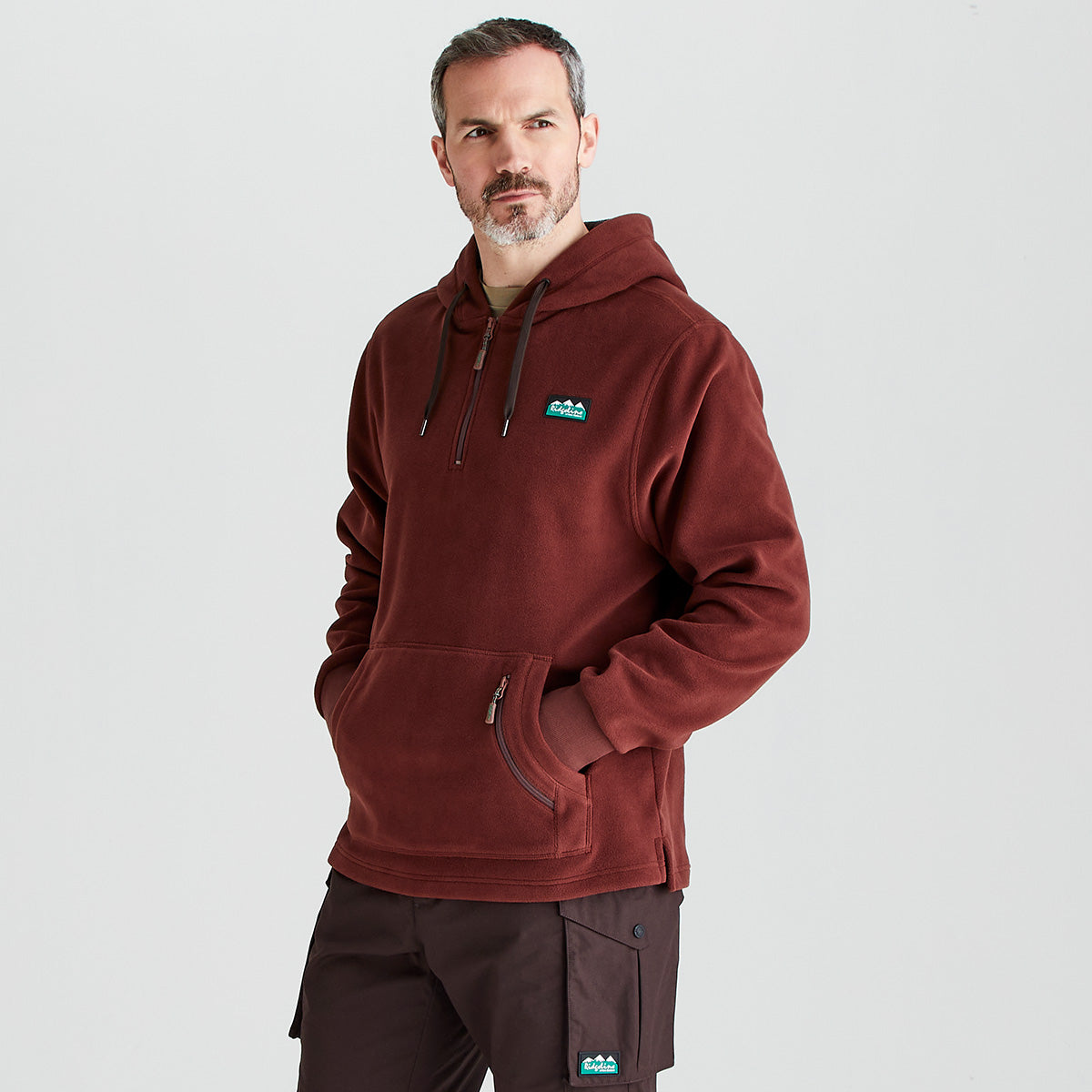 Man wearing a maroon hoodie with a logo on a light gray background
