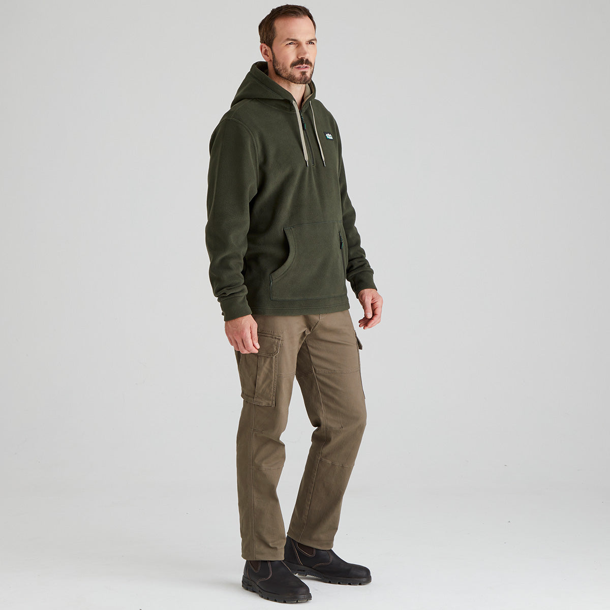 Man wearing a green fleece hoodie and brown pants on a white background